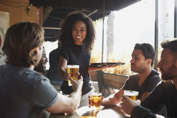 女服务员在体育酒吧为一群男性朋友提供饮料 — 图库照片