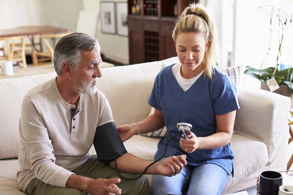 Gesundheitshelferin Macht Hausbesuch Bei Einem Älteren Mann Der Blutdruck Nimmt — Stockfoto