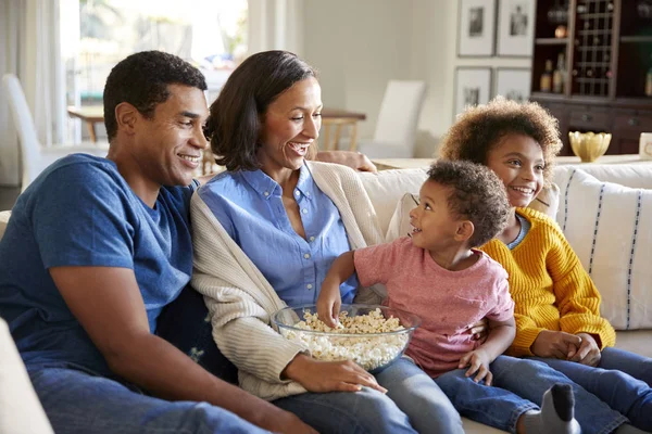 ポップコーンを食べる幼児の少年は 一緒に映画を見て リビングルームで彼の妹と両親とソファに座って — ストック写真