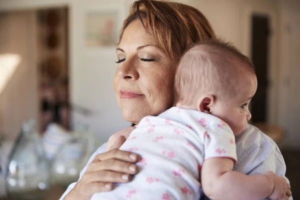 中年祖母闭上眼睛抱着她刚出生的孙子 头和肩膀 — 图库照片