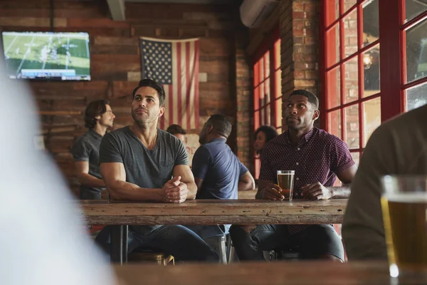 男性の友人は ビールを飲んで スポーツバーで画面上のゲームを見て — ストック写真