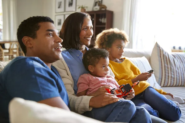 年轻的家庭一起坐在客厅的沙发上看电视 有选择地集中注意力 — 图库照片