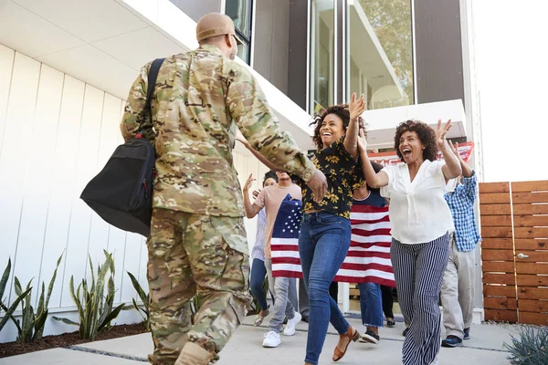 Family welcoming back millennial black soldier returning home, low angle view