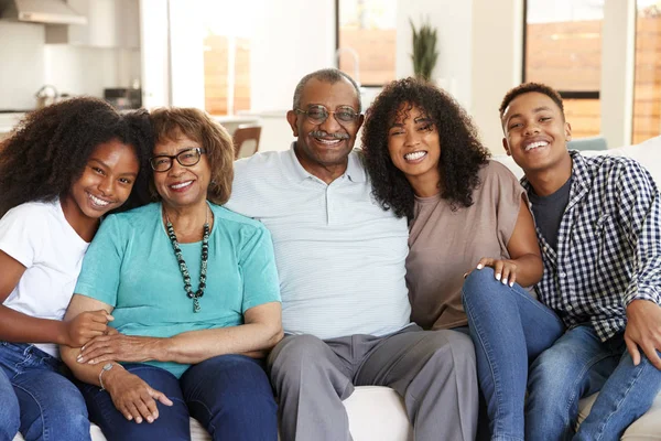 Abuelos Con Adolescentes Nietos Adultos Jóvenes Sentados Casa Sonriendo Cámara —  Fotos de Stock