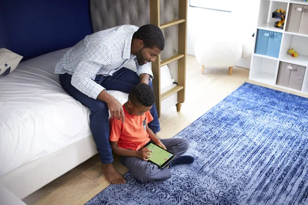 父亲与儿子坐在卧室玩游戏的数字平板电脑一起 — 图库照片
