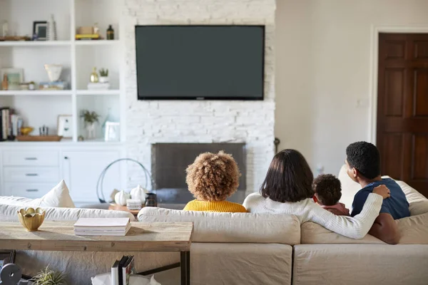 ソファに座って リビングルームで一緒にテレビを見ている若い家族のバックビュー — ストック写真