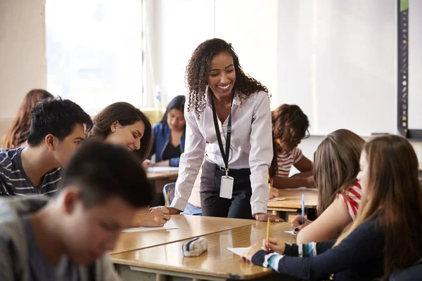 Vrouwelijke Middelbare School Leraar Staande Door Student Tabel Les — Stockfoto