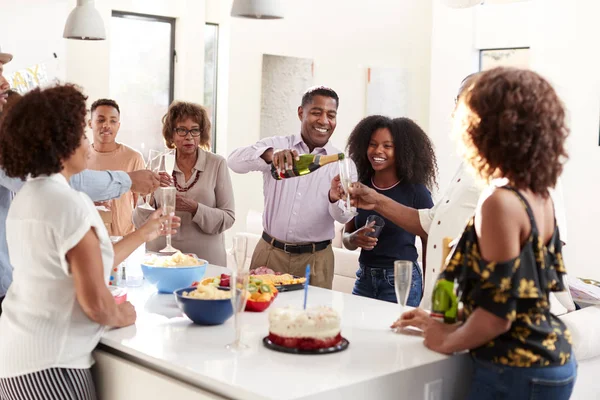 自宅でお祝いの間に乾杯するためにメガネを上げる3世代の黒人家族 — ストック写真