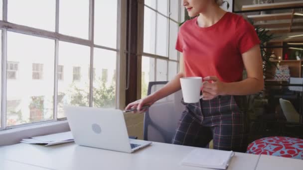 若いヒスパニック系の女性がカップと電話でオフィスに入り 仕事に机に座って クローズアップ — ストック動画