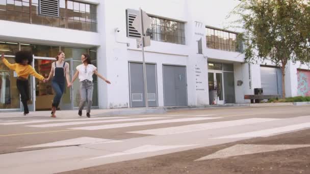 三个千禧年女友手牵手 笑着穿过人行横道 — 图库视频影像
