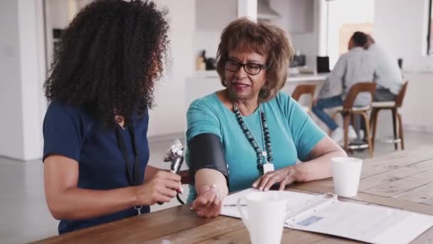 Pekerja Kesehatan Perempuan Memeriksa Tekanan Darah Seorang Perempuan Senior Selama — Stok Video