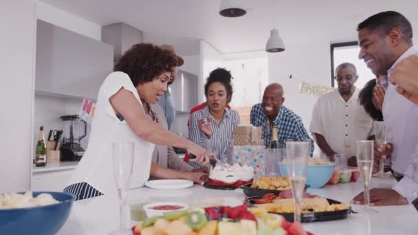 母が誕生日パーティーでケーキを切っている間 三世代の黒人家族がテーブルの周りに立つ — ストック動画