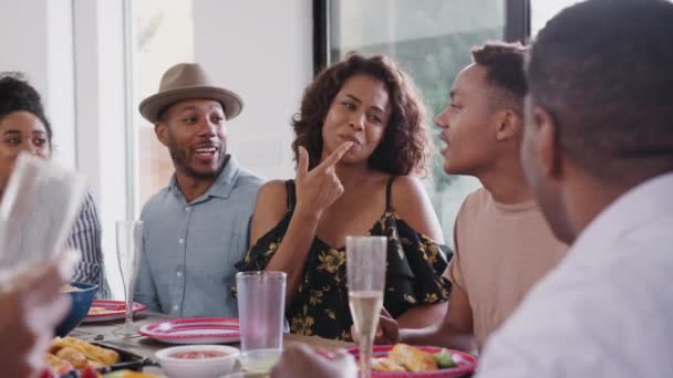 家族のお祝いの間に話す夕食のテーブルで一緒に座っている3世代の黒人家族 — ストック動画