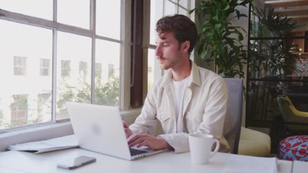 Миллениальный Белый Креативный Мужчина Сидящий Столом Ноутбуком Офисе Панорамный Снимок — стоковое видео