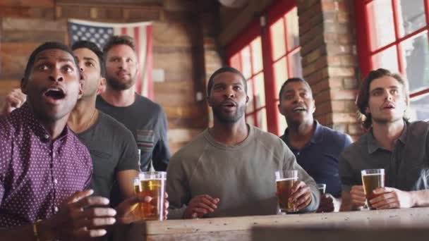 一群男性朋友坐在体育酒吧内喝啤酒 在屏幕上观看比赛 慢动作拍摄 — 图库视频影像