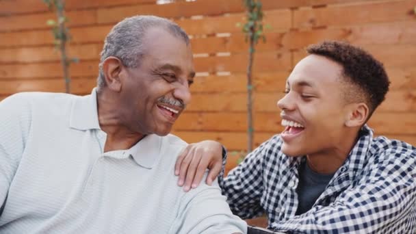 屋外で彼の若い大人の孫と笑う先輩黒人男性 クローズアップ — ストック動画