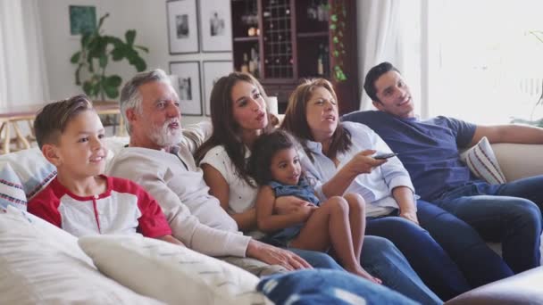 Три Покоління Латиноамериканського Сімейства Сидять Дивані Дивляться Телевізор Бабуся Допомогою — стокове відео