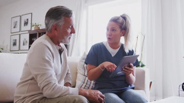Kvinnlig Sjukvårdspersonal Använder Tablet Sittande Med Senior Hispanic Man Ett — Stockvideo