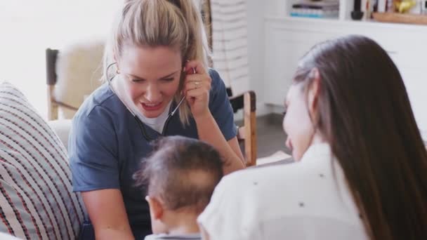 Женщина Медицинский Работник Молодой Мамой Младенцем Сына Дома Используя Стетоскоп — стоковое видео