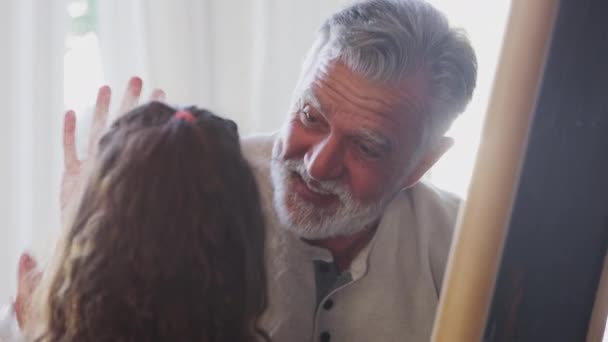 Homem Sênior Brincando Com Sua Neta Enquanto Ela Desenha Quadro — Vídeo de Stock