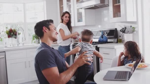 彼らの台所で若いヒスパニックの家族 コンロでお母さんの料理 空気中の赤ちゃんを持ち上げるお父さんは クローズアップ — ストック動画