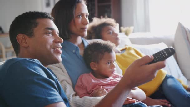 年轻的家庭坐在一起 坐在客厅的房间里看电视 侧视图 — 图库视频影像