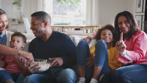 ソファに座ってテレビを見てポップコーンを食べている3世代のアフリカ系アメリカ人の家族 パンニングショット — ストック動画