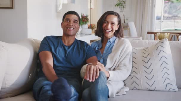 年轻的成年非洲裔美国夫妇坐在他们的客厅看电视一起笑 — 图库视频影像