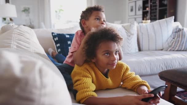 Προ Teen Κορίτσι Κείτεται Στον Καναπέ Βλέποντας Τηλεόραση Μικρότερος Αδελφός — Αρχείο Βίντεο