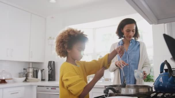 彼女の母親と食べ物を準備台所のコンロに立っている前十代のアフリカ系アメリカ人の女の子 低角度のビュー — ストック動画