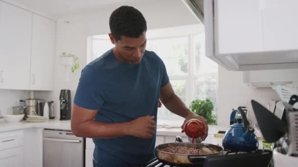 Ung Vuxen Afrikansk Amerikansk Man Matlagning Köket Lägga Tomatsås Till — Stockvideo