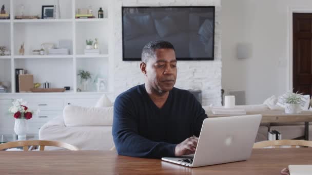自宅でラップトップコンピュータを使用してテーブルに座っている中年のアフリカ系アメリカ人男性は クローズアップ ズームイン — ストック動画
