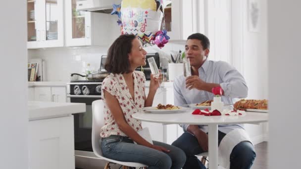 一緒にロマンチックな食事を食べる前に キッチンのテーブルに座って乾杯する若いカップル — ストック動画