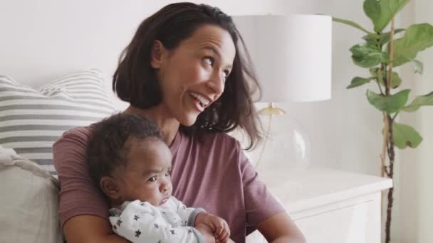 幸せなミレニアルアフリカ系アメリカ人の母親は 彼女の赤ちゃんを抱いてベッドに座って クローズアップ — ストック動画