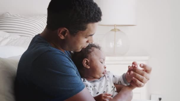 ミレニアルアフリカ系アメリカ人のお父さんは 彼の赤ちゃんの男の子を保持する肘掛け椅子で揺れ 閉じて 側面のビュー — ストック動画