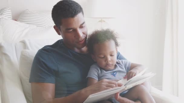 Millennial Padre Afroamericano Sentado Leyendo Libro Con Hijo Pequeño Vista — Vídeos de Stock