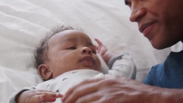 千禧年非洲裔美国父亲躺在床上亲吻他的小儿子 — 图库视频影像