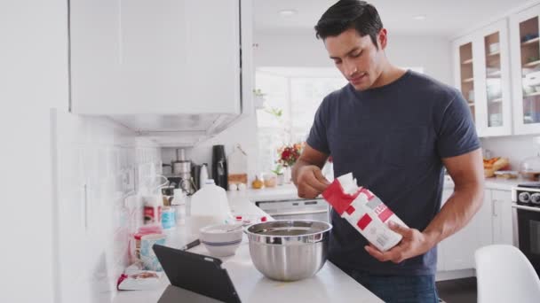 Millennial Man Förbereder Kaka Mix Efter Ett Recept Tablet Lägga — Stockvideo