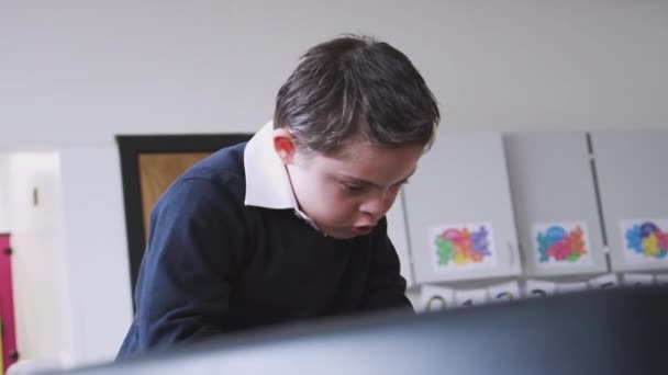 Lågstadieskola Skolpojke Med Syndrom Stående Vid Skrivbordet Ett Klassrum Spelar — Stockvideo