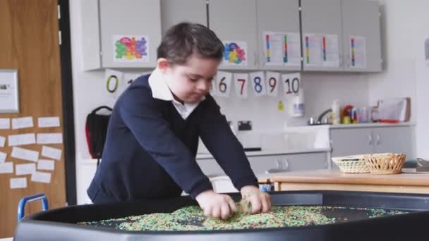 Grundschüler Mit Syndrom Steht Mit Einer Sensorischen Spielwanne Klassenzimmer Seitenansicht — Stockvideo