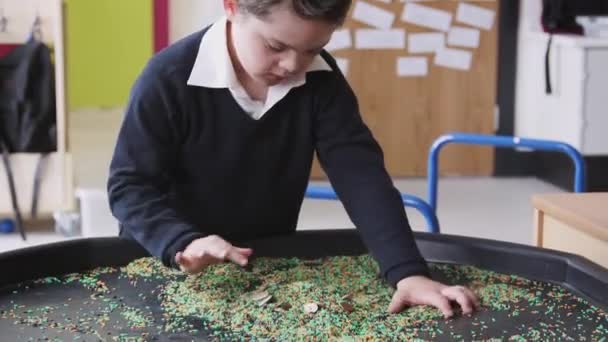 Primary Schoolboy Syndrome Stands Using Sensory Play Tub Classroom Close — Stock Video