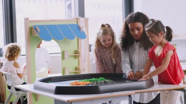 Zwei Schülerinnen Stehen Mit Einer Lehrerin Einem Sensorischen Spieltisch Einem — Stockvideo