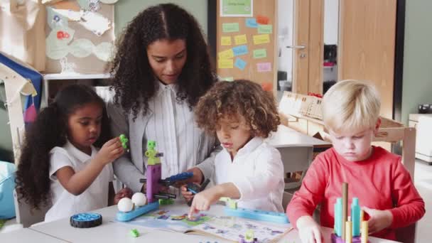 Professor Escola Infantil Feminino Ajudando Crianças Usando Brinquedos Construção Sala — Vídeo de Stock