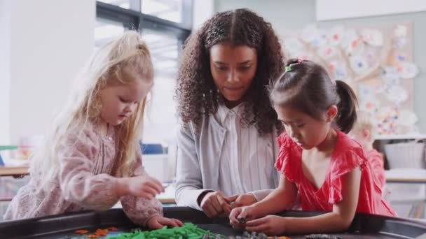 Två Skolflickor Sensorisk Lek Bord Med Kvinnlig Lärare Ett Spädbarn — Stockvideo