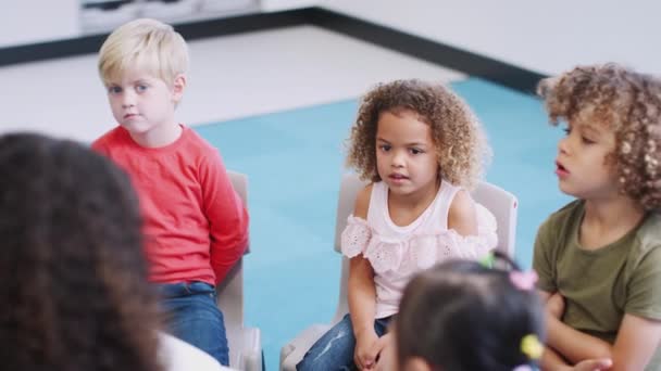 Niños Escuela Infantil Sentados Sillas Aula Escuchando Lectura Maestro Vista — Vídeos de Stock