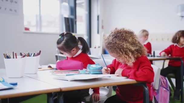 幼児学校の教室で机で働く制服の若い女の子 クローズアップ 低角度 — ストック動画