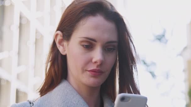 年轻的白人妇女站在伦敦阳光明媚的街道上 使用她的智能手机 低角度的特写 — 图库视频影像