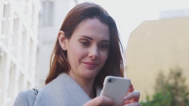 年轻的白人妇女站在伦敦阳光明媚的街道上 用她的智能手机打电话 低角度 — 图库视频影像