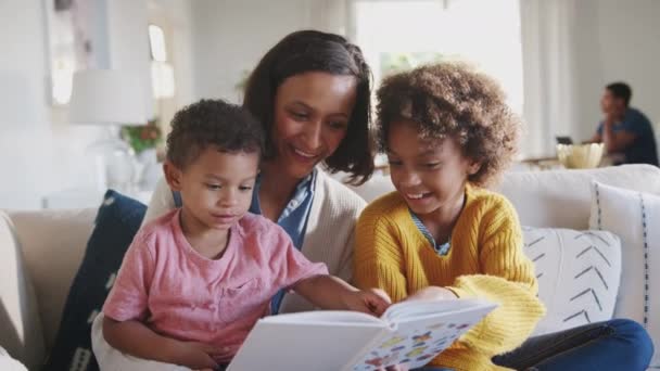 Молодая Афроамериканская Мама Читает Книгу Двумя Детьми Отец Сидит Столом — стоковое видео