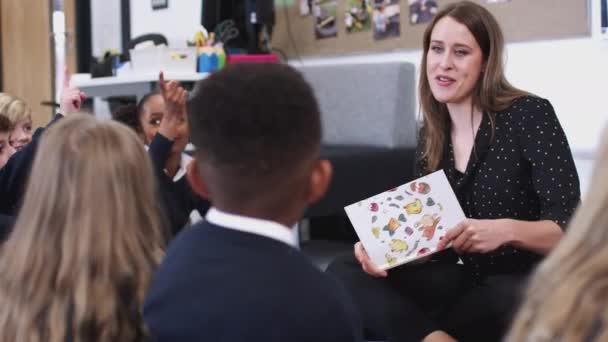 Profesora Leyendo Libro Para Niños Primaria Sentados Piso Clase Enfoque — Vídeos de Stock